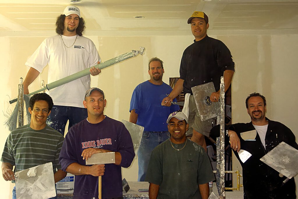 Home Toronto School of Drywall students holding drywall finishing tools in a classroom training area.