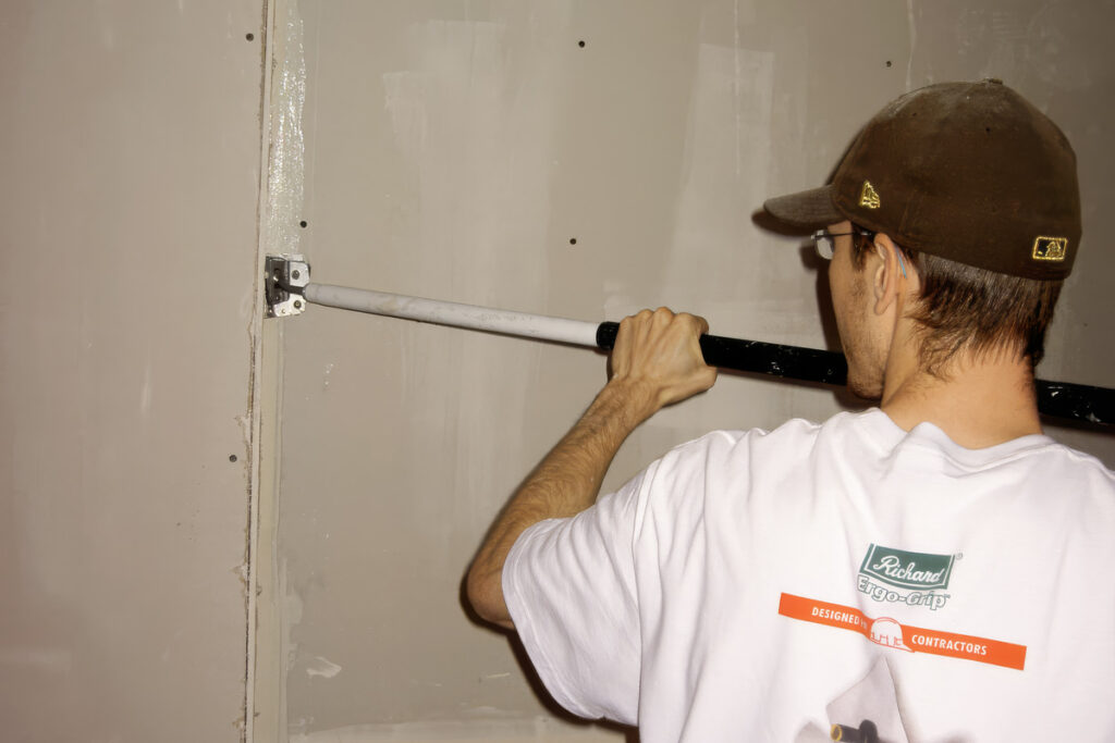 Home Student using a drywall flusher pole during Toronto School of Drywall hands-on training.